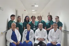 Ekip mjekësh dhe infermierësh me uniforma jeshile në korridor